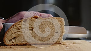 Close Up of freshly baked bread being sliced with a bread knife in Slow Motion.