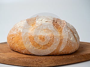 A close-up of freshly baked wheat bread with a crispy crust lies on a wooden tray. Side view, bakery concept