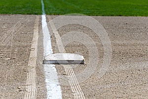 Close up of freshly chalked baseline, with base plate, dirt and grass, empty baseball field on a sunny day