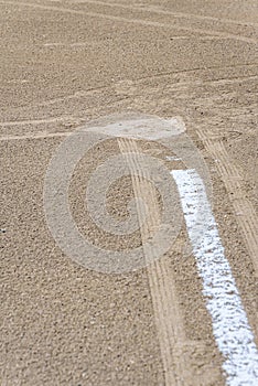 Close up of freshly chalked baseline leading to home plate, dirt only, empty baseball field on a sunny day