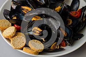 Close up of freshly cooked mussels with crisp bread and tomato. Healthy food concept. Selective focus