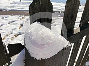 Close up of freshly fallen snow on top of a wooden fence post