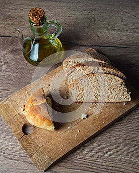 Close up of freshly sliced bread on a wooden cutting board with an olive oil pitcher next to it