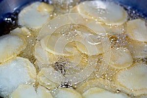 Close-up of fried chips potatoes frying in boiling hot oil in a deep fryer at home. fast fries, Junk food concept