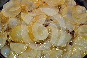 A close up of fried chips potatoes frying in boiling hot oil in a deep fryer at home. fast fries, Junk food concept