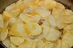 A close up of fried chips potatoes frying in boiling hot oil in a deep fryer at home. fast fries, Junk food concept, home made