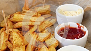 Close up. Fried potatoes with spices, sauces and fresh beer on the background. Wooden table in an Irish pub