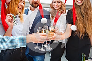 Close-up friends drinking on a Christmas party on a blurred background. New Year celebration concept.