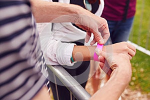 Close Up Of Friends At Entrance To Music Festival Putting On Security Wristbands