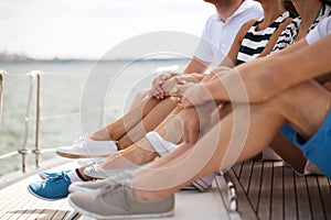Close up of friends legs sitting on yacht deck