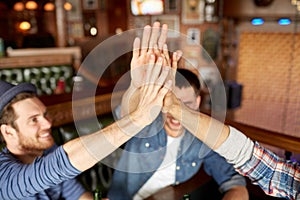 Close up of friends making high five at bar or pub