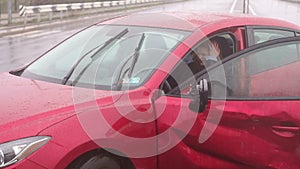 Close-up of a frightened girl sitting in the car after an accident in the rain.