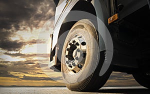 Close-up, Front a big truck wheel, tire of semi truck parked at sunset sky. Industry freight truck transportation