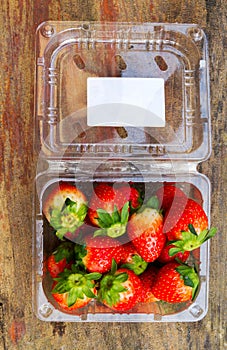close up front focus of fresh strawberries on the table and inside plastic box on wooden background