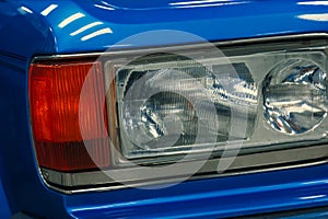 Close-up of front halogen headlights of blue car in garage