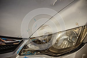 Close-up front of new silver car distorted by accident. Crashed