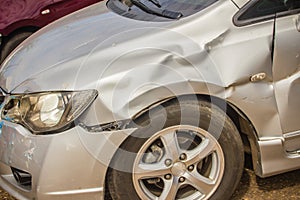 Close-up front of new silver car distorted by accident. Crashed