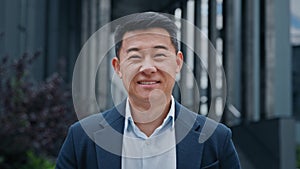 Close up front view in city outdoors Asian Korean man business boss leader company CEO smiling glad happy middle-aged