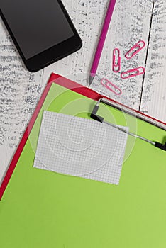 Close up front view colored clipboard blank paper sheet sticky note clips smartphone pencil lying retro old wooden