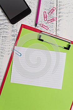 Close up front view colored clipboard blank paper sheet sticky note clips smartphone pencil lying retro old wooden