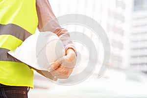 Close up front view of engineering male construction worker holding safety white helmet