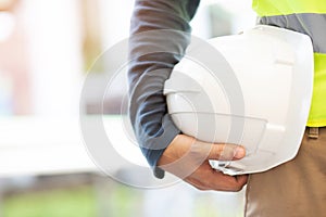 Close up front view of engineering male construction worker stand holding safety white helmet and wear reflective clothing for the