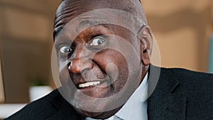 Close up front view male wrinkled elderly face emotional funny frightened puzzled African business man looking at camera