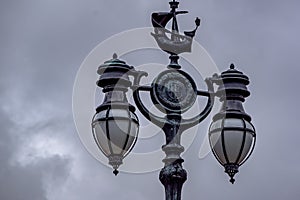 Close up front view of old black street lamp with cloudy sky in the background.
