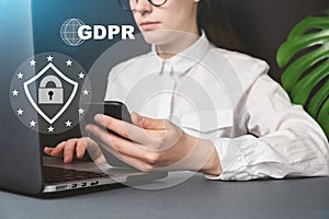 Close up front view young woman holding smartphone with text GDPR. Data Protection Regulation, sitting at desk near pc. photo