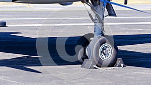 Close-up of front wheels of airplane with chock, Airplane parked at the airport, aircraft undercarriage. Detail of nose wheel