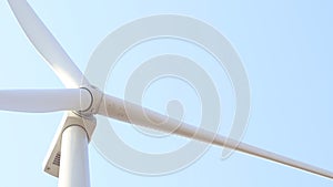 Close - up of a front of a white rotor of a wind generator with a clear blue sky on the background.