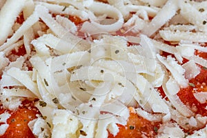 Close-up on frozen grated cheese on frozen pizza