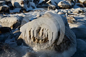 Close-up of frozen water surface with hoarfrost, bubbles trapped with natural cracks and green algae at the bottom of a