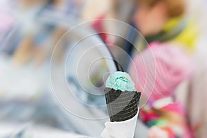 Close-up of fruit Ice-cream green color in Black waffle cone, background with sweet dessert. Real scene in store