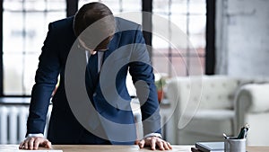 Close up frustrated businessman standing at desk with head down