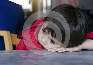 Close up frustrated young kid, Lonely little boy sitting alone and looking down with bored face,Unhappy Preschool child with sad