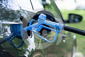Close up of fuel cell car with connected hydrogen fueling nozzle.