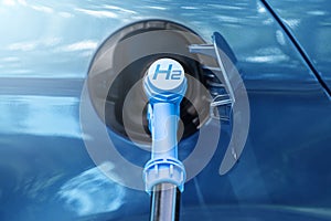Close up of fuel cell car with connected hydrogen fueling nozzle.