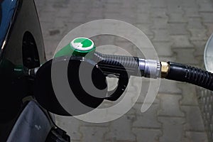 Close up fueling gun in a dark car gas tank