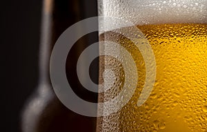 Close up of a full beer glass cold beer condensation with a defocused bottle detail