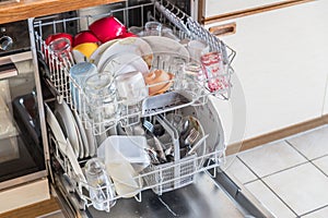 Close up of a fully stocked dishwasher in a kitchen with dishes glasses bowls knives forks spoons cutlery, Germany