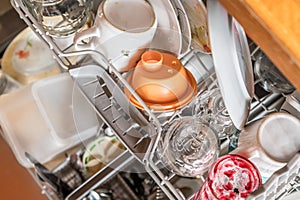 Close up of a fully stocked dishwasher in a kitchen with dishes glasses bowls knives forks spoons cutlery, Germany