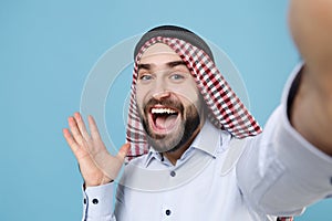 Close up of funny bearded arabian muslim man in keffiyeh kafiya ring igal agal casual clothes isolated on pastel blue