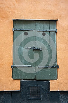 Close up of funny face like green wooden window shutter on building exterior.