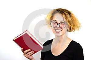 Close-up of a funny girl student with glasses slid down her nose and a strange hairstyle, a mess on her head, holding a