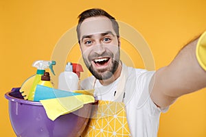 Close up of funny man househusband in apron hold basin with detergent bottles washing cleansers doing housework isolated