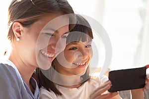 Close up funny mother and daughter looking at smartphone screen