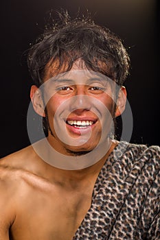 Close up of funny prehistoric man smiling to the camera in a black background