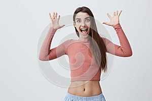 Close up of funny young good-looking brunette cheerful girl with long hair in pink shirt and blue trousers spreading