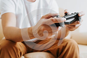 Close-up of gamer's male hands holding wireless game controller with joysticks.